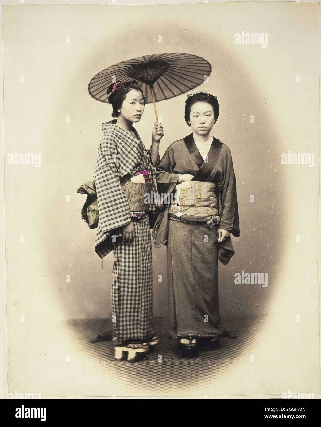 Two women with a parasol, in traditional costume and footwear, Japan, taken between 1867 and 1869 by Felice A Beato. Stock Photo