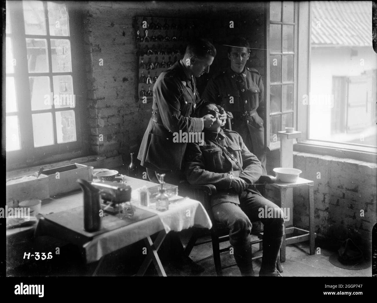 A soldier, seated, has a set of new dentures fitted by a dentist attached to the New Zealand Dental Corps. Stock Photo