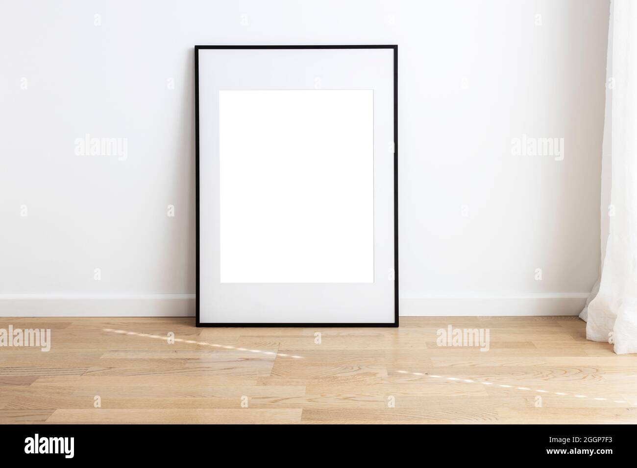 Rectangular mock up frame with passepartou standing in a room with wooden flooring. Stock Photo