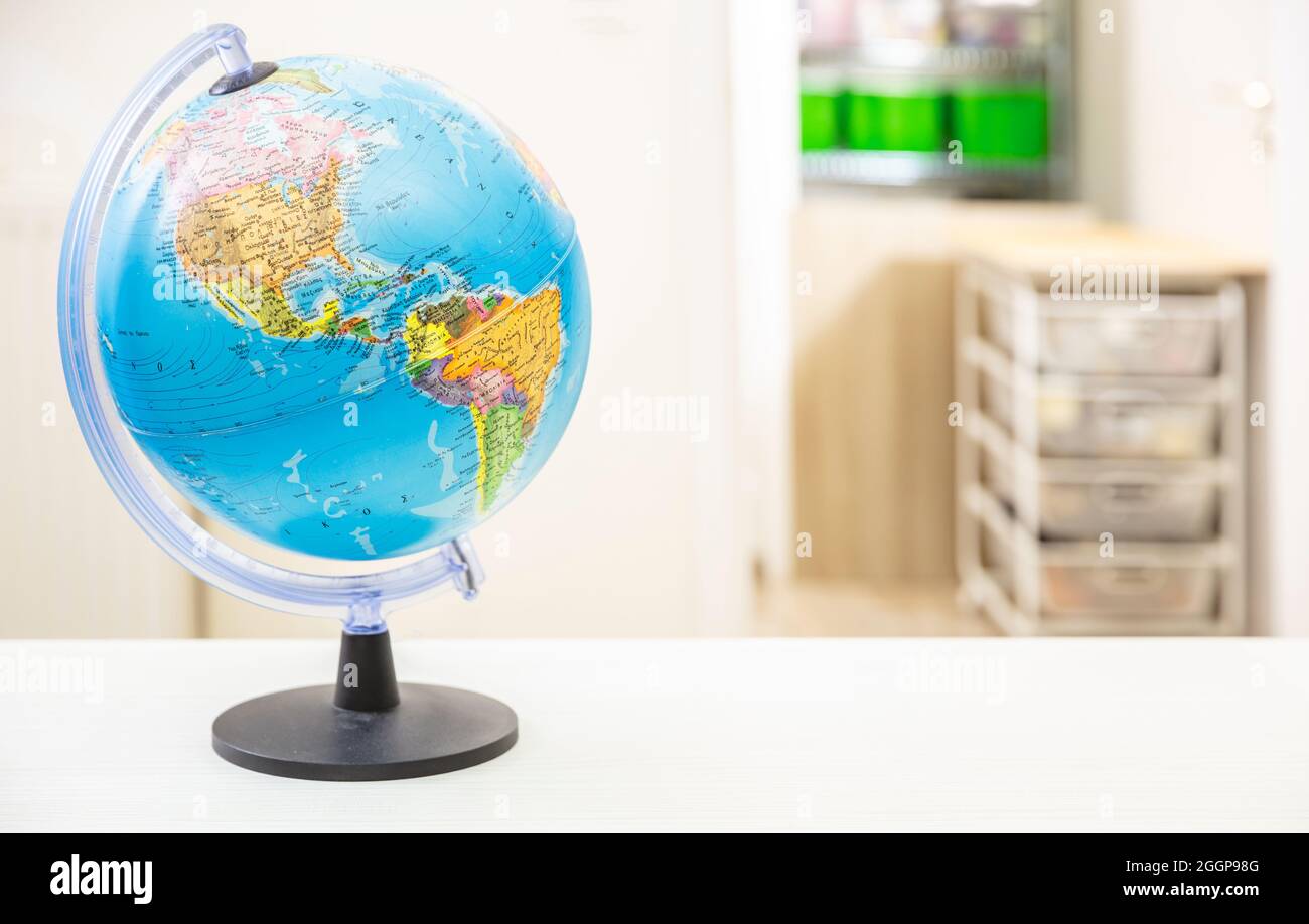 Globe school planet Earth on student desk, blur room interior background. Education, cartography, countries and world political map, back to school co Stock Photo