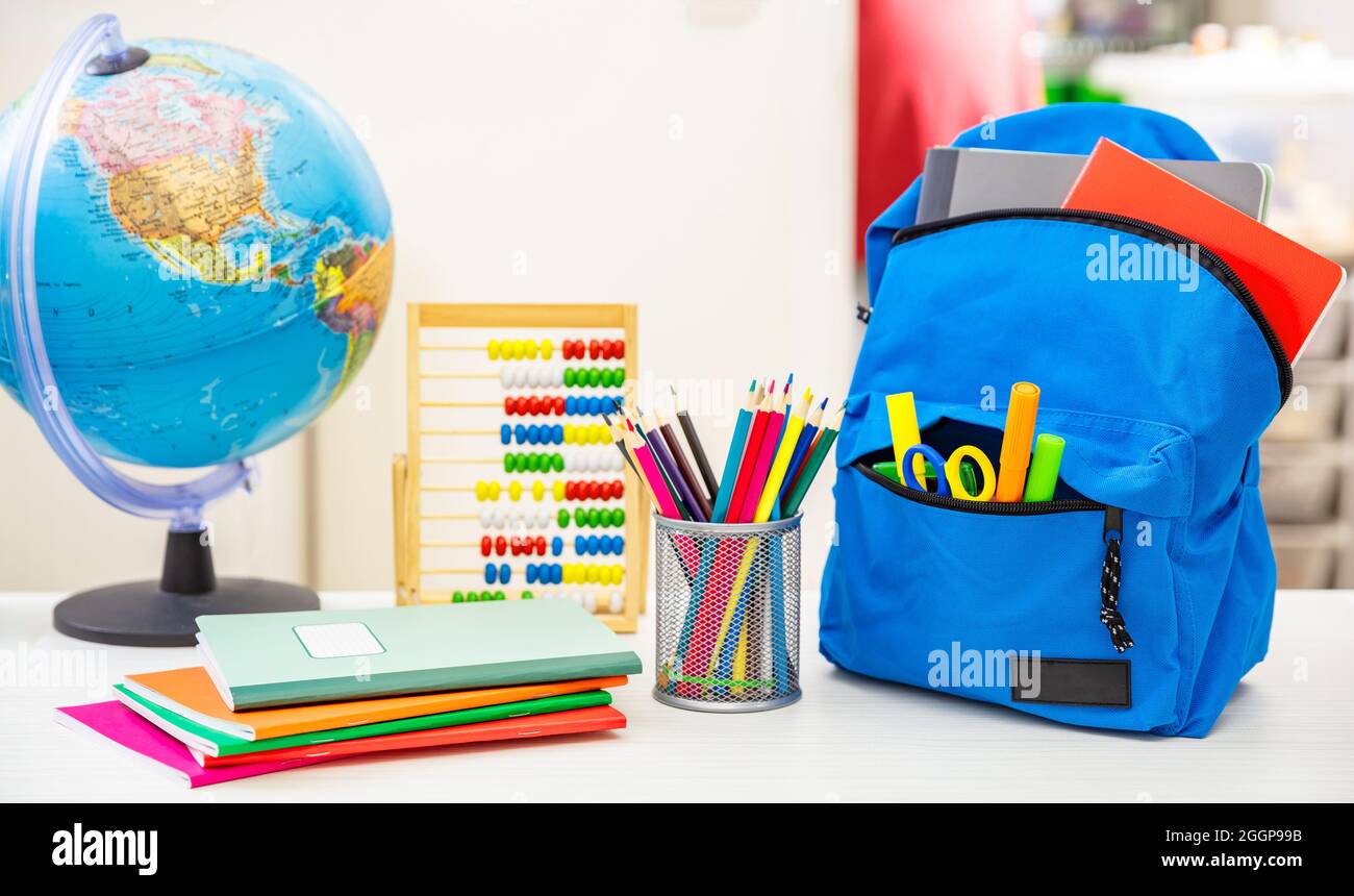 Back to school. Student backpack and supplies on white desk, blur interior room background. Education, study concept Stock Photo