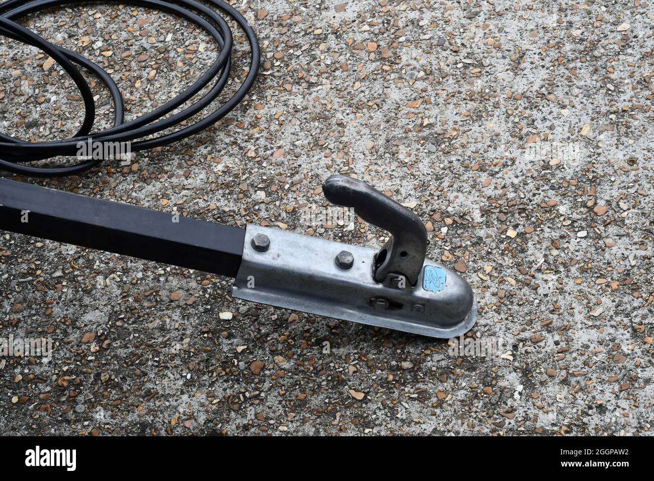 A trailers towing arm sat on a concrete roadway with the electrical cable by the side Stock Photo