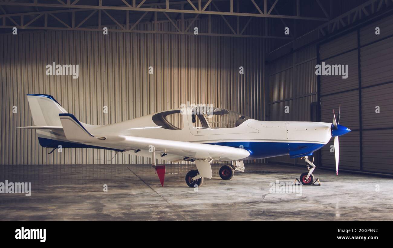 Small white private jet parked in the hangar Stock Photo