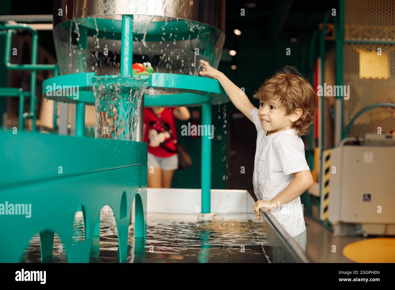 Boy plays with water on children's water equipment in entertainment center. Educational games . Tactile sensations. Children's emotions and joy .Worki Stock Photo