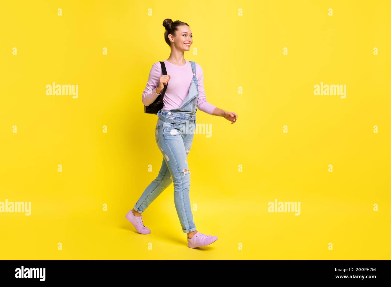 Full size profile photo of optimistic nice brunet lady go wear overall isolated on yellow background Stock Photo