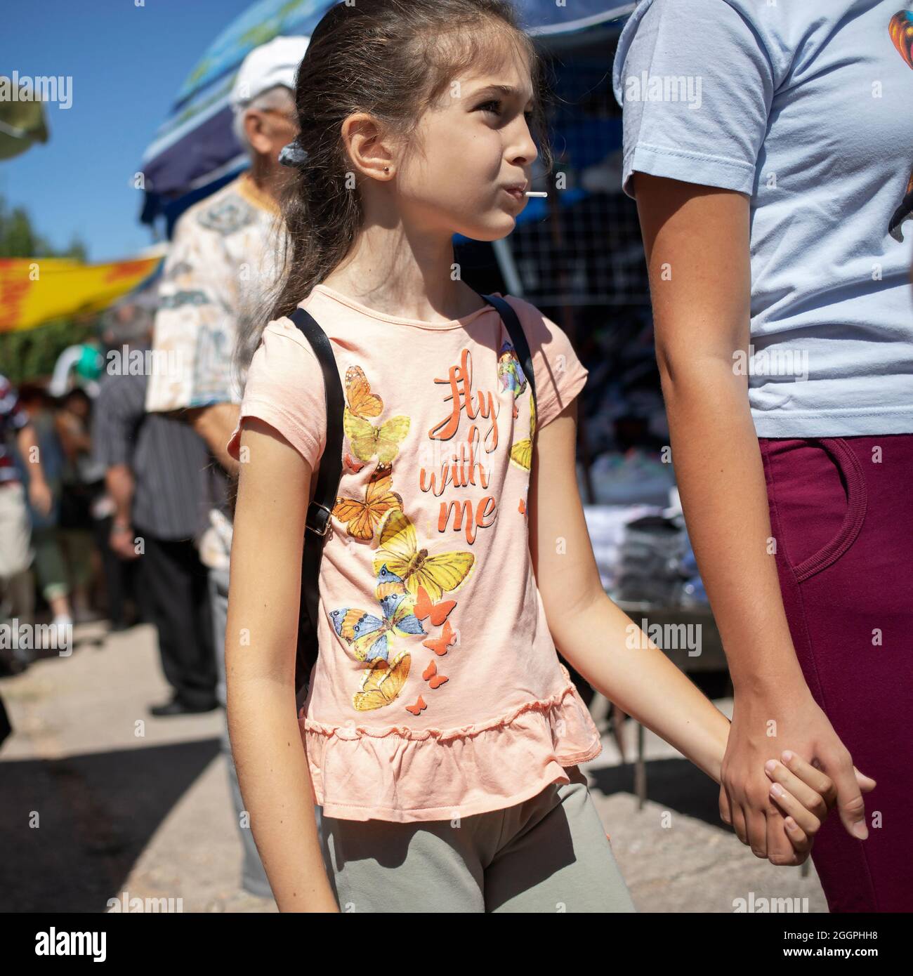Sokobanja, Serbia, Aug 19, 2021: Portrait of a girl with a lollipop touring a village fair with mom Stock Photo