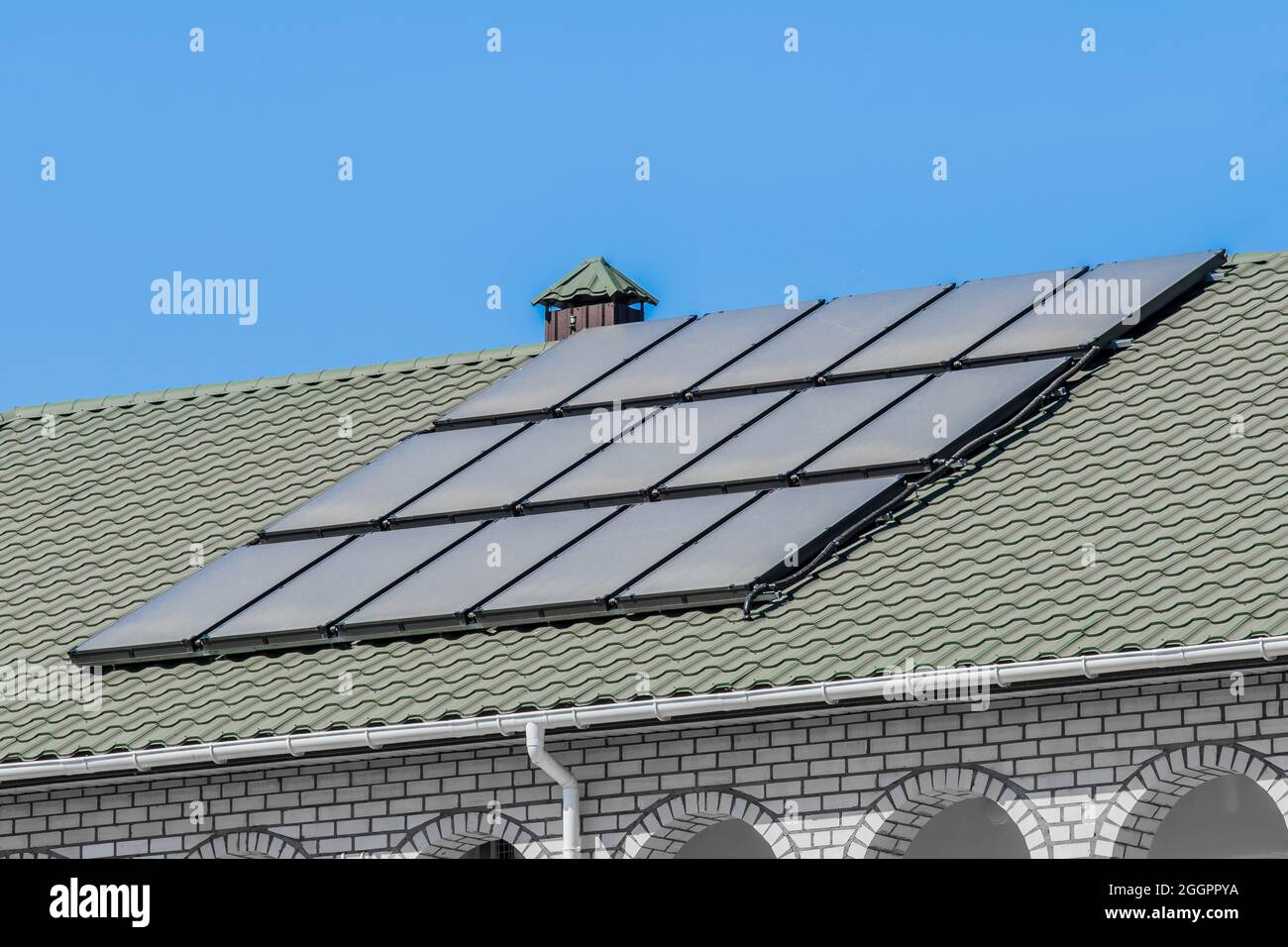 Thermal solar panels alternative technologies of water heating on the roof of the hotel against the blue sky outdoor. Stock Photo