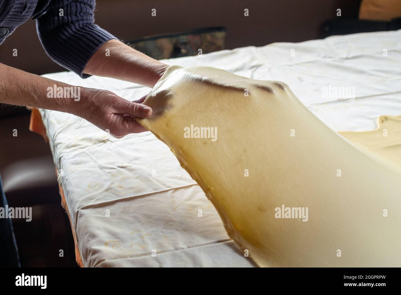 Stretching dough for strudel over  kitchen table Stock Photo