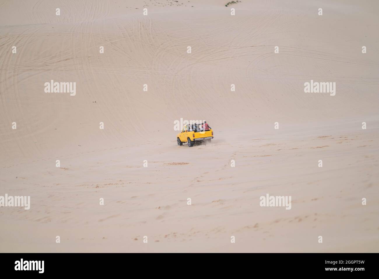 Amazing view of big car driving on sandy dunes and tire tracks on sand on sunny day during summer vacation. Sand dunes. Tourists in desert. Stock Photo