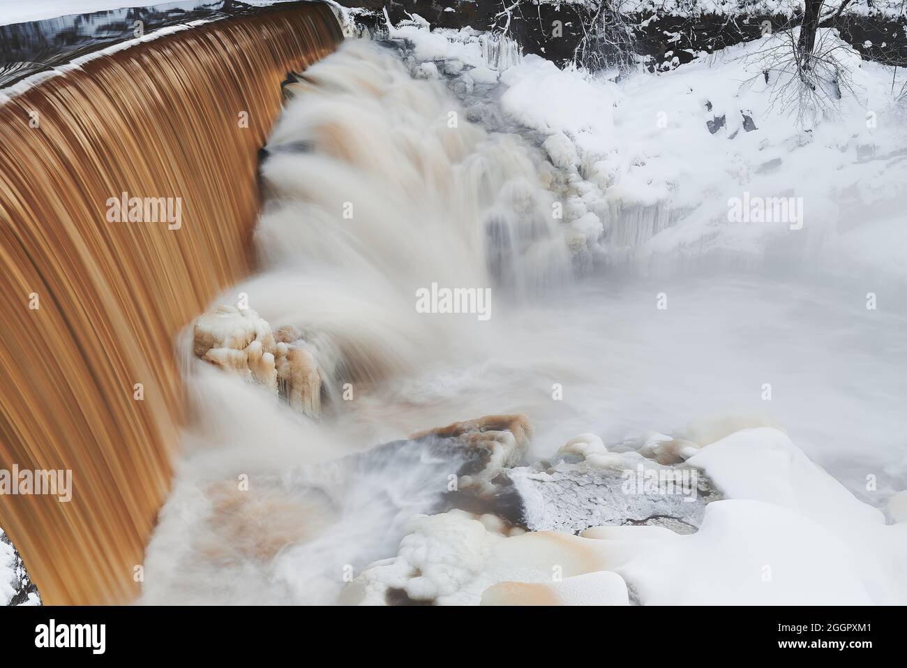 Water pours over the dam and icy rocks in the mouth of Vantaa River at the Vanhankaupunginkoski rapids (Vanhankaupunginkosken putous) extremely cold w Stock Photo