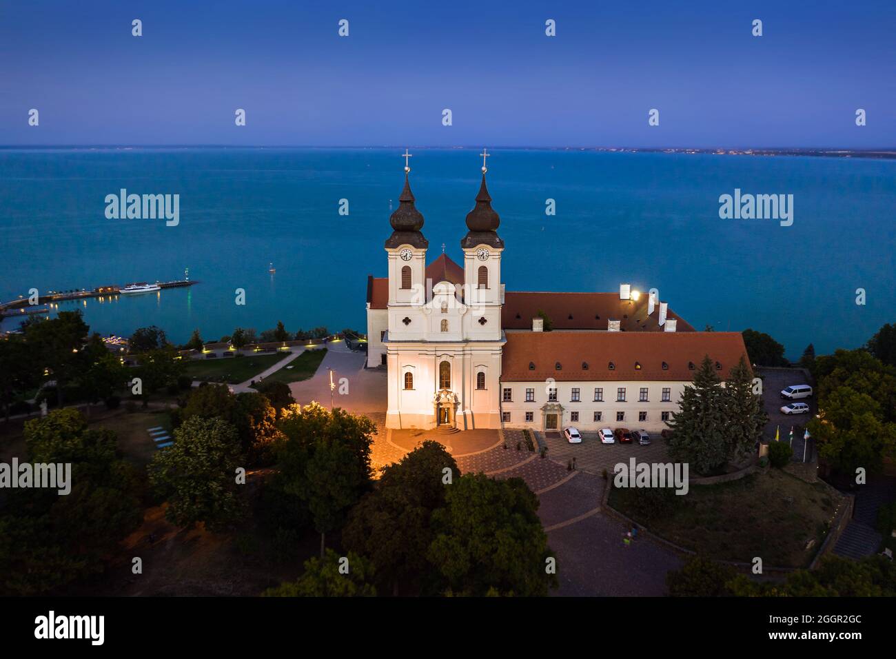 Tihany, Hungary - Aerial view of the illuminated Benedictine Monastery of Tihany (Tihany Abbey, Tihanyi Apatsag) with clear blue sky at dusk over Lake Stock Photo