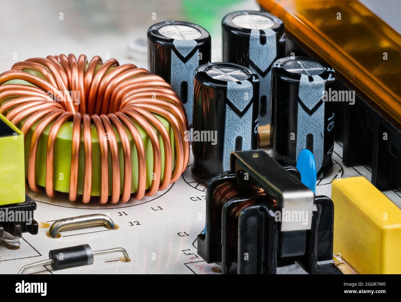 Toroidal core inductor, transformer or electrolytic capacitors on PCB detail. Electric components on printed circuit board of switch-mode power supply. Stock Photo