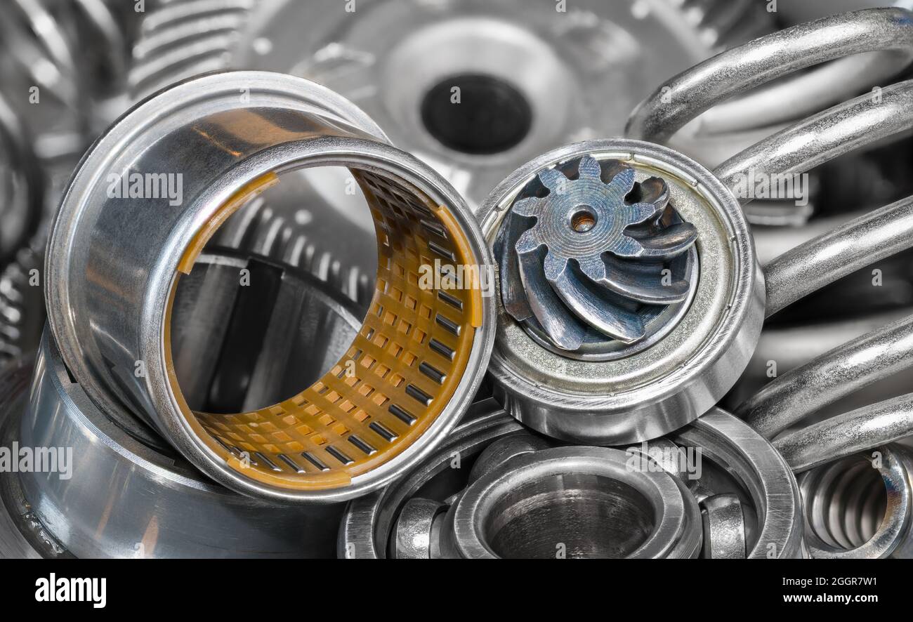 Detail a heap of hardware spare parts of a gear machine mechanism. Needle rolling bearing bushing with small steel rollers in cylindrical plastic cage. Stock Photo