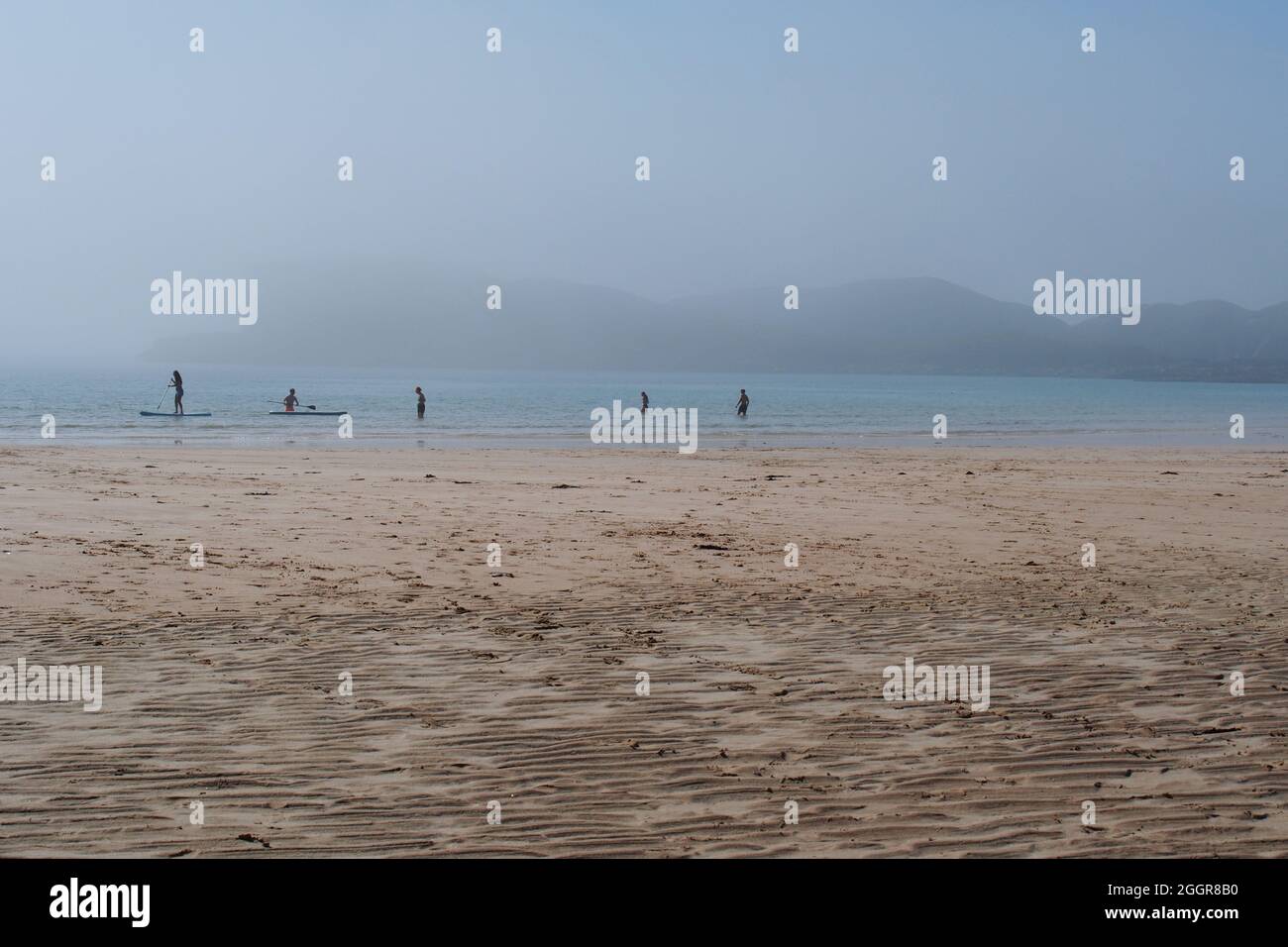 People enjoying the sea and beach on a staycation in Oldshoremore, Kinlochbervie, northwest Scotland, as a sea mist sweeps in over the beach Stock Photo