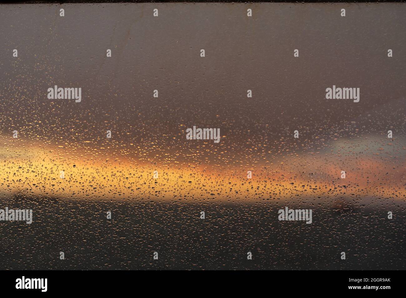 sunrise lights reflecting on rain drops on window at wheel house of ship Stock Photo