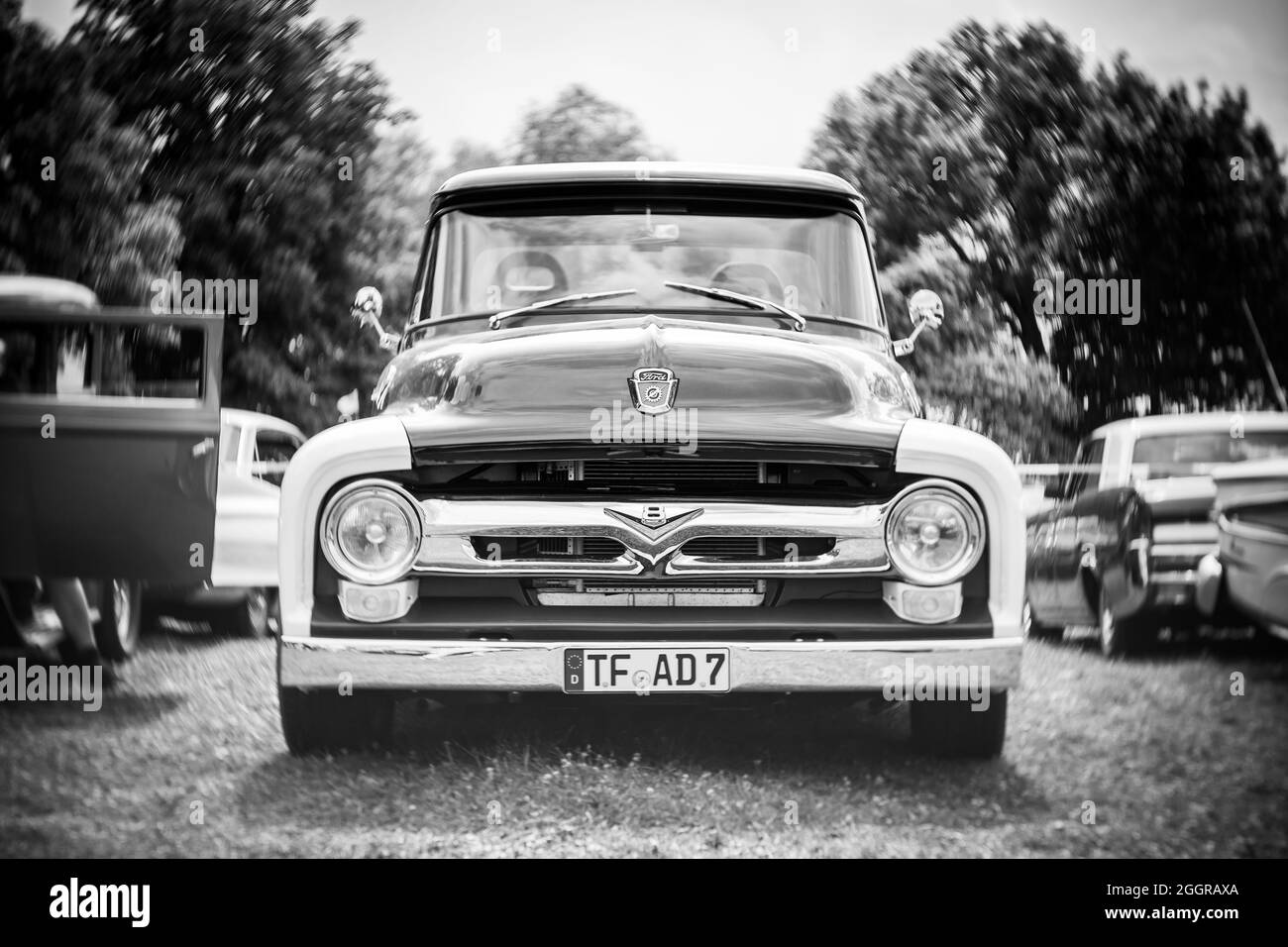 Full-size pickup truck Ford F-150, 1956, (second generation). Focus on center. Swirly bokeh. Black and white. The exhibition of 'US Car Classics'. Stock Photo