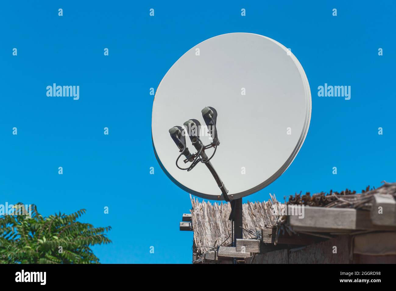 Satellite dish antenna communication and tv signal technology on the roof of the house against the background of blue sky. Stock Photo