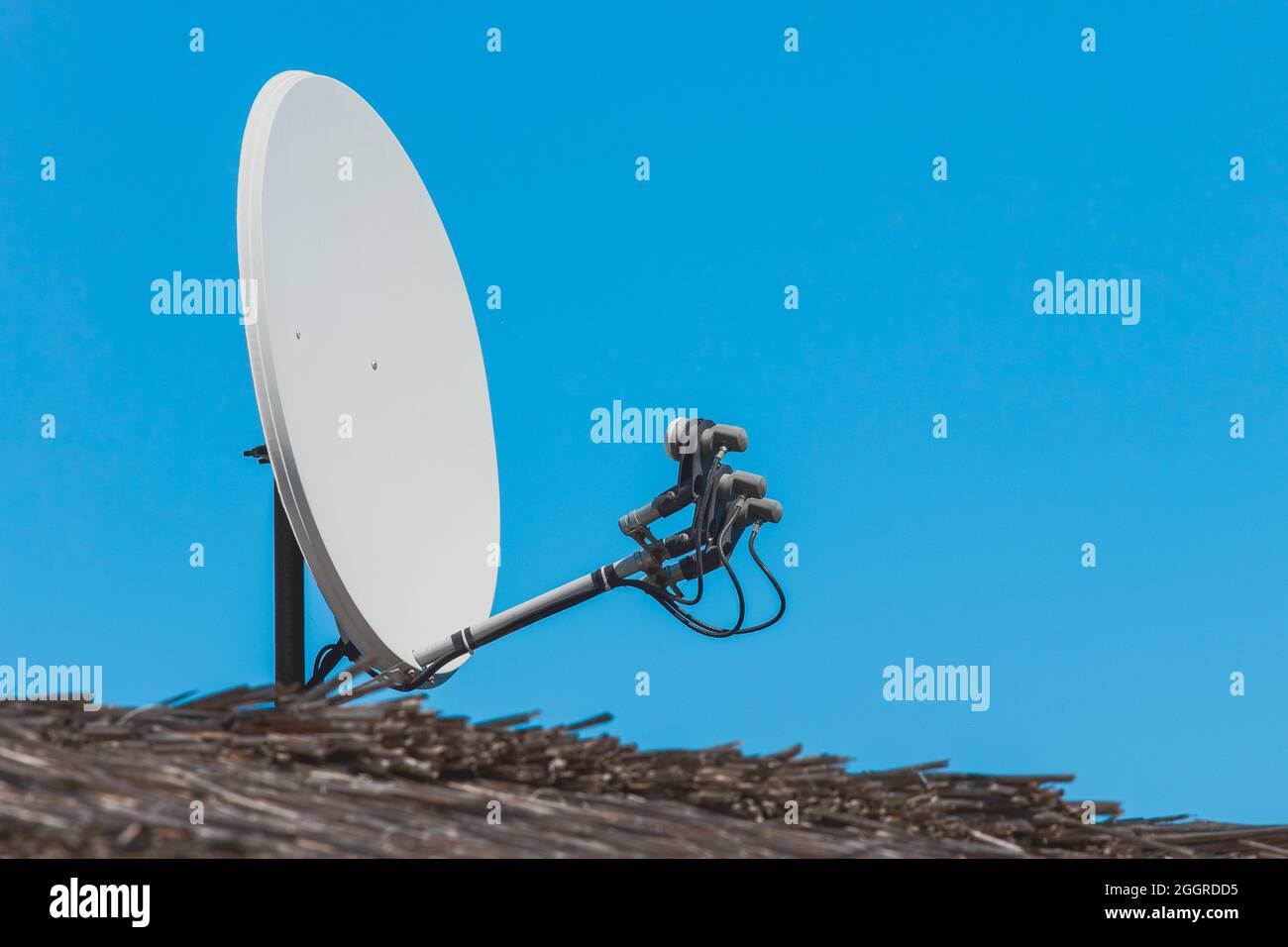 Satellite dish antenna communication and tv signal technology on the roof of the house against the background of blue sky. Stock Photo