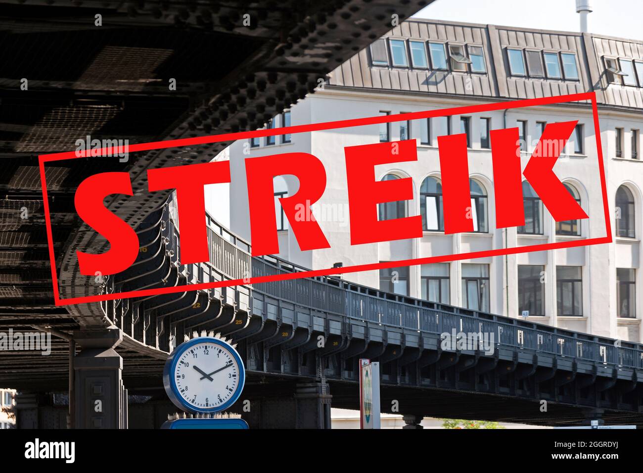 Banner with German text Streik (meaning strike) over an image with a clock under the curve of a suburban railway bridge in the city of Hamburg, German Stock Photo