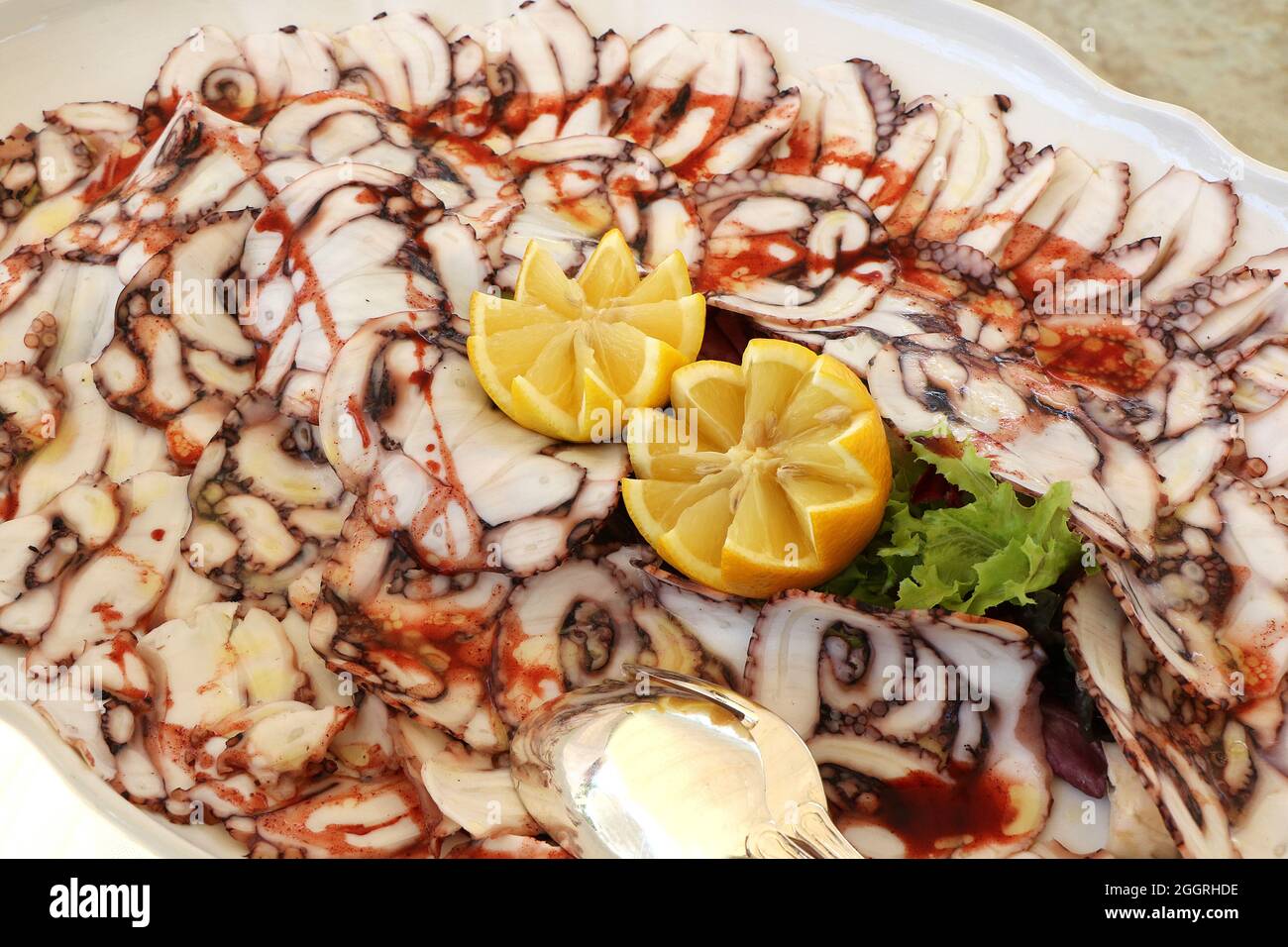 Octopus carpaccio dish with lemon and salad Stock Photo