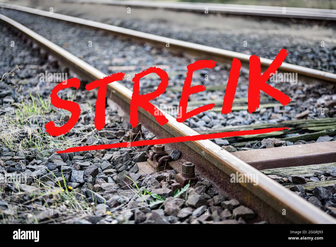 German text Streik (meaning strike) over rusty metal railway tracks and  brackets in a ballast bed, selected focus, narrow depth of field Stock  Photo - Alamy