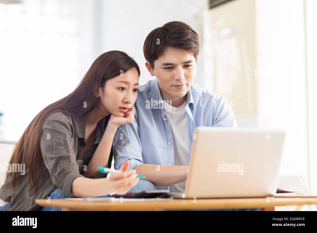 Young couple planning budget,looking at laptop screen, checking finances. Stock Photo