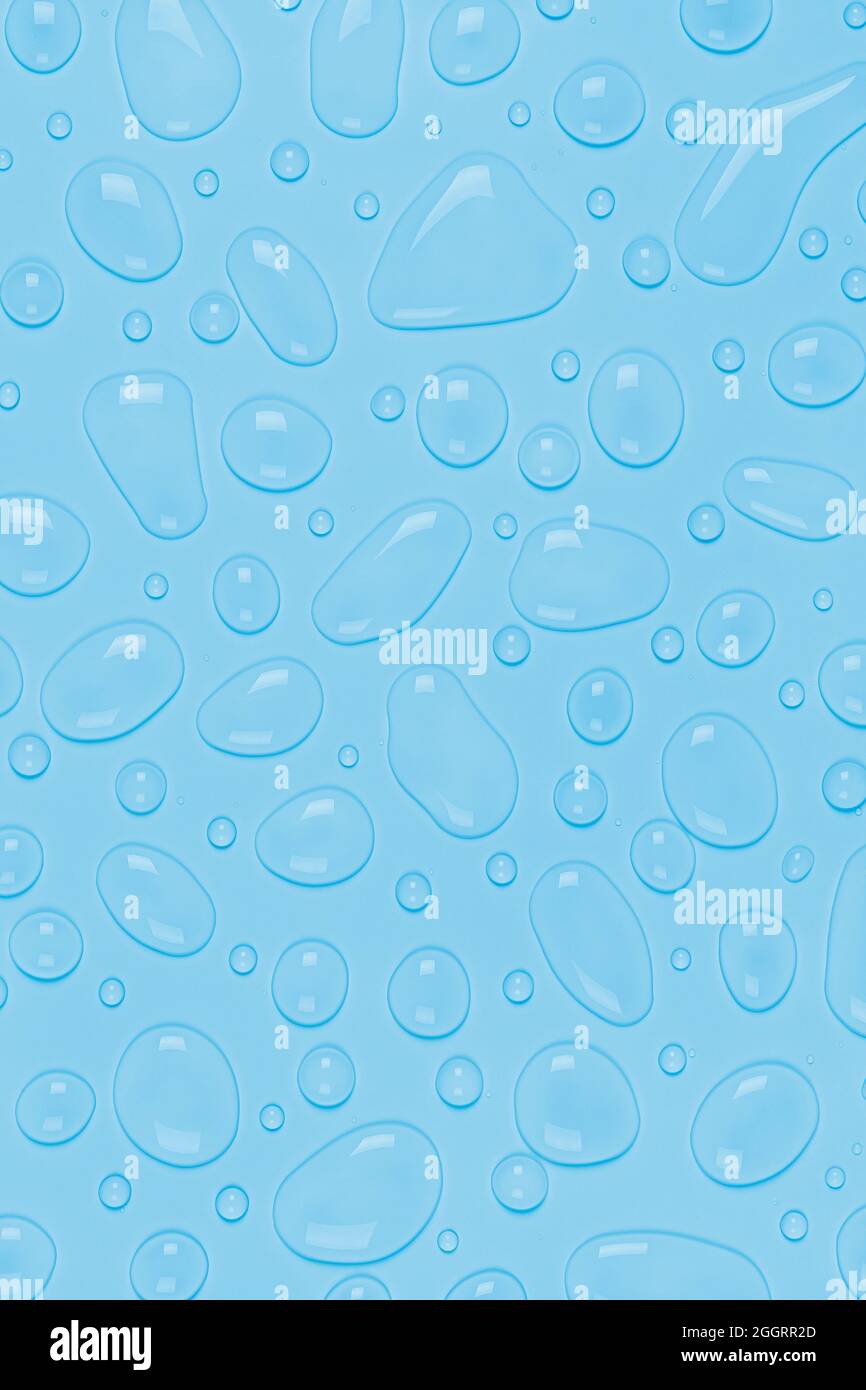 Water drops on a pastel blue vertical background. Water texture close ...