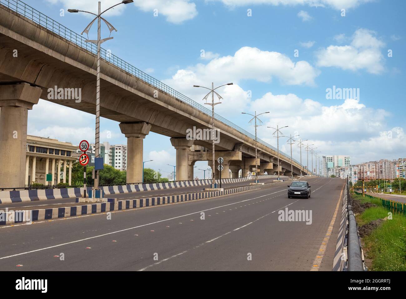 Early morning traffic on city road with view of flyover and commercial and residential buildings at Rajarhat area Kolkata, India. Stock Photo