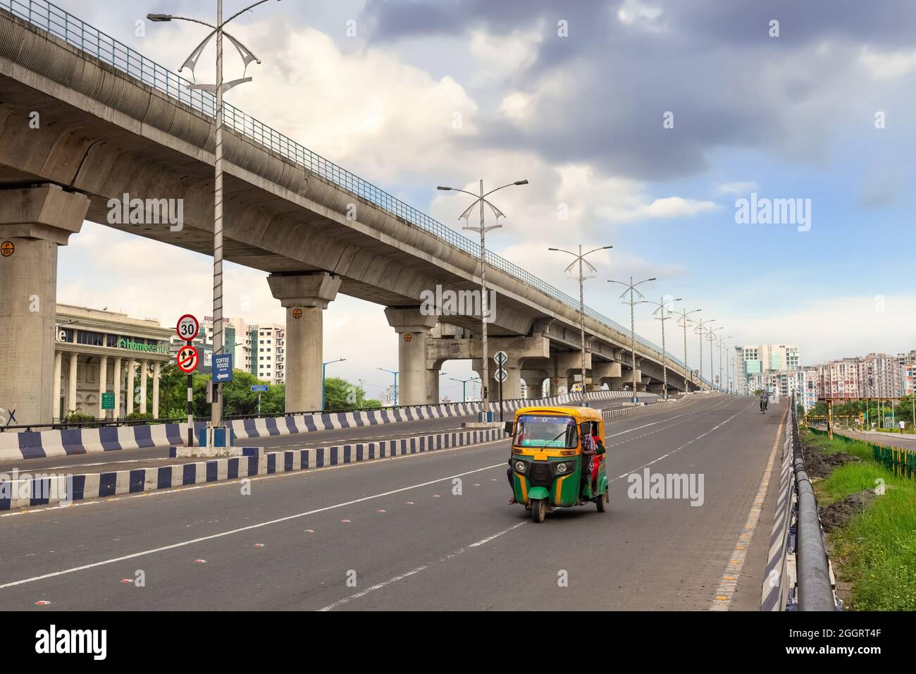 Auto rickshaw with passengers on city road with view of over bridge and commercial buildings at Rajarhat area Kolkata Stock Photo