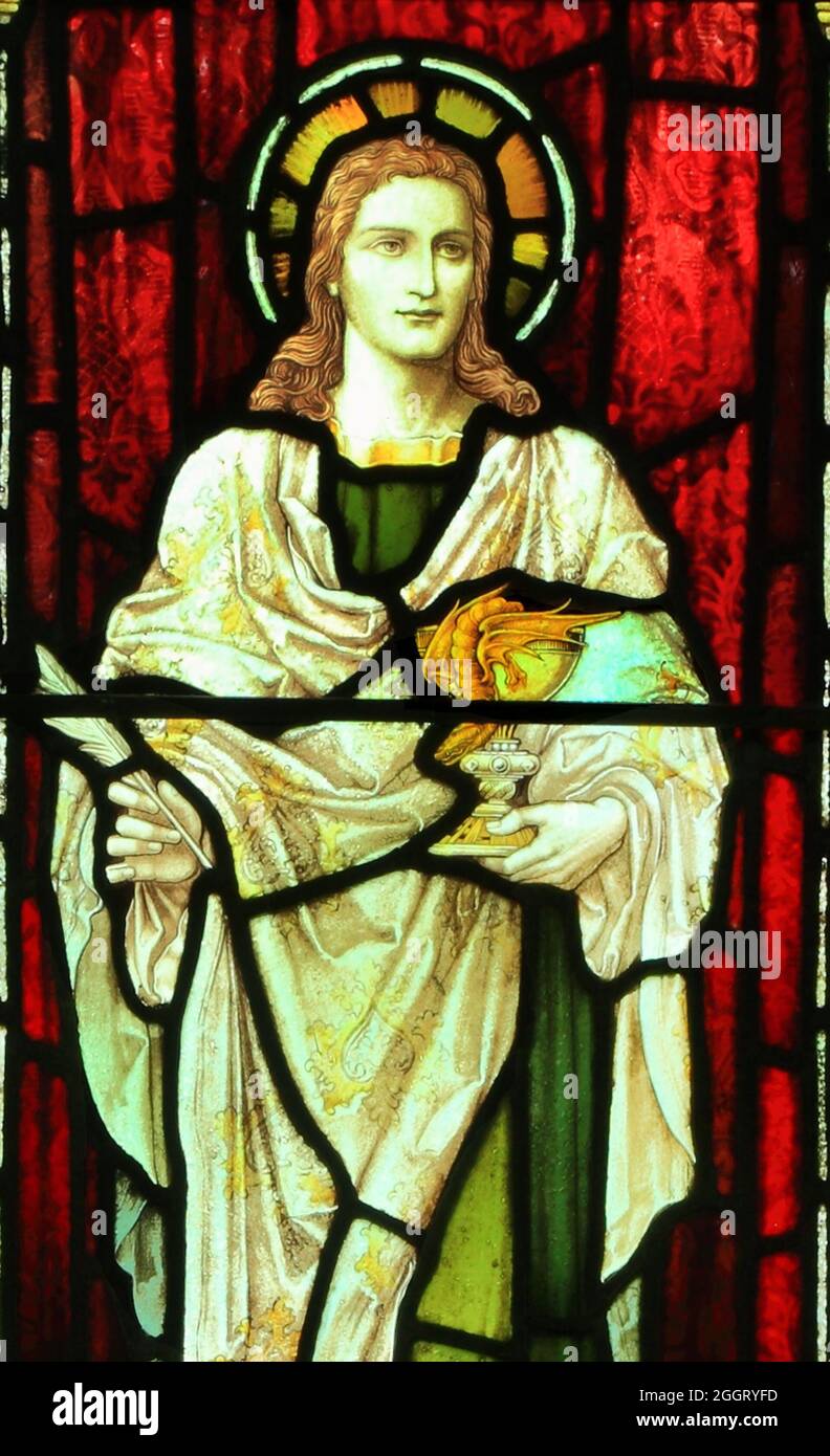 Saint John, holding wine cup, goblet, glass, with snake, stained glass window, saints, Snettisham church, Norfolk, England Stock Photo