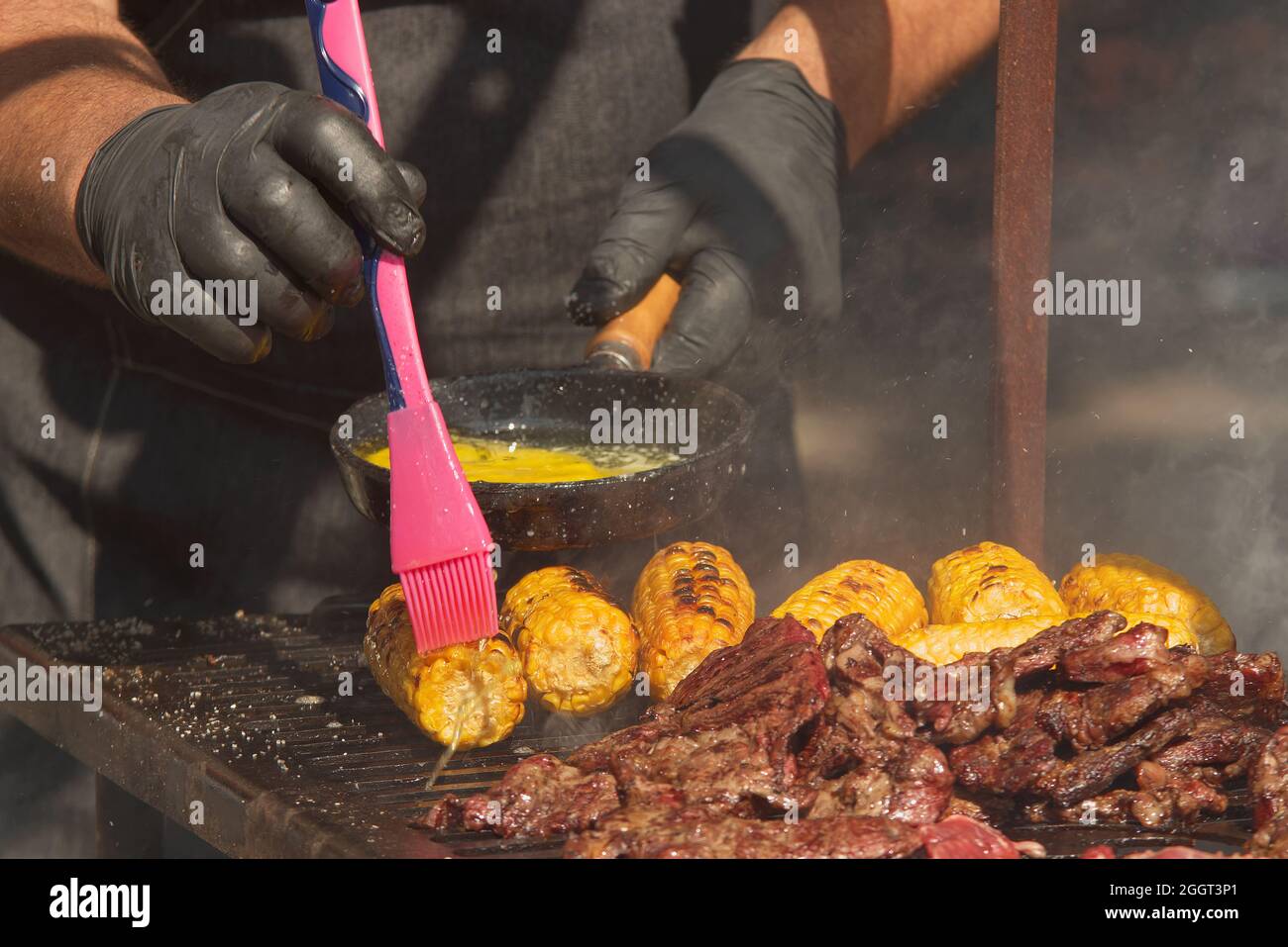 The chef brushes the cobs of corn on the grill with melted butter Stock