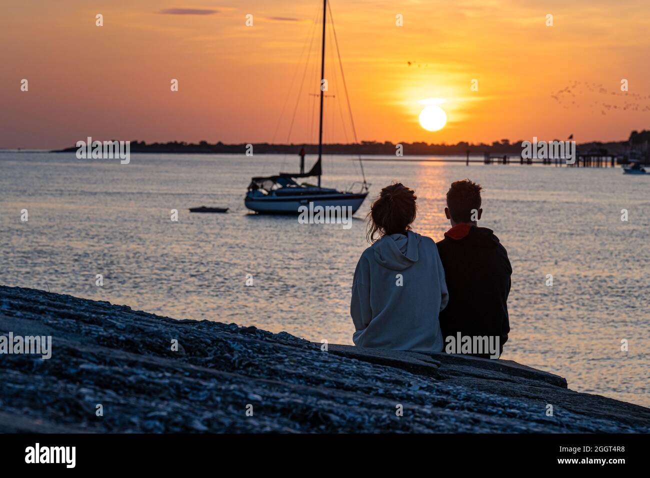 Young couple watching the sun rise over Matanzas Bay and Anastasia Island from the Castillo de San Marcos waterfront in St. Augustine, Florida. (USA) Stock Photo