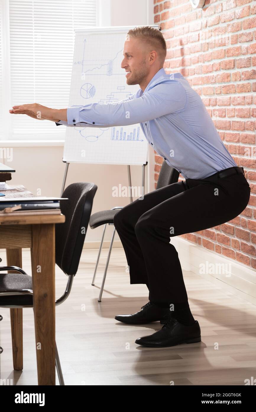 Workplace Exercise At Office Desk. Fit Man Doing Sit Up Stock Photo