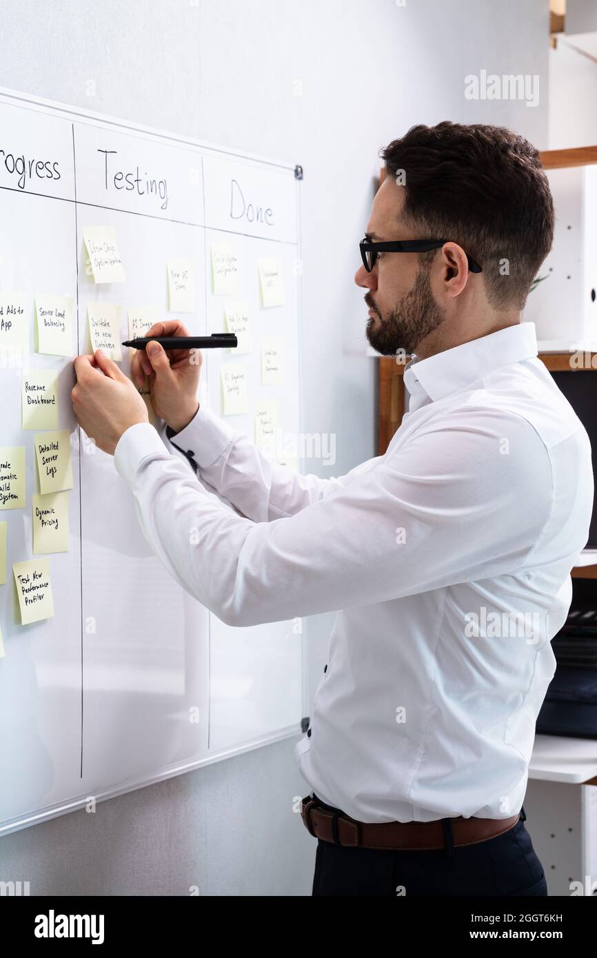 Man Writing Notes On Kanban Board In Office Stock Photo