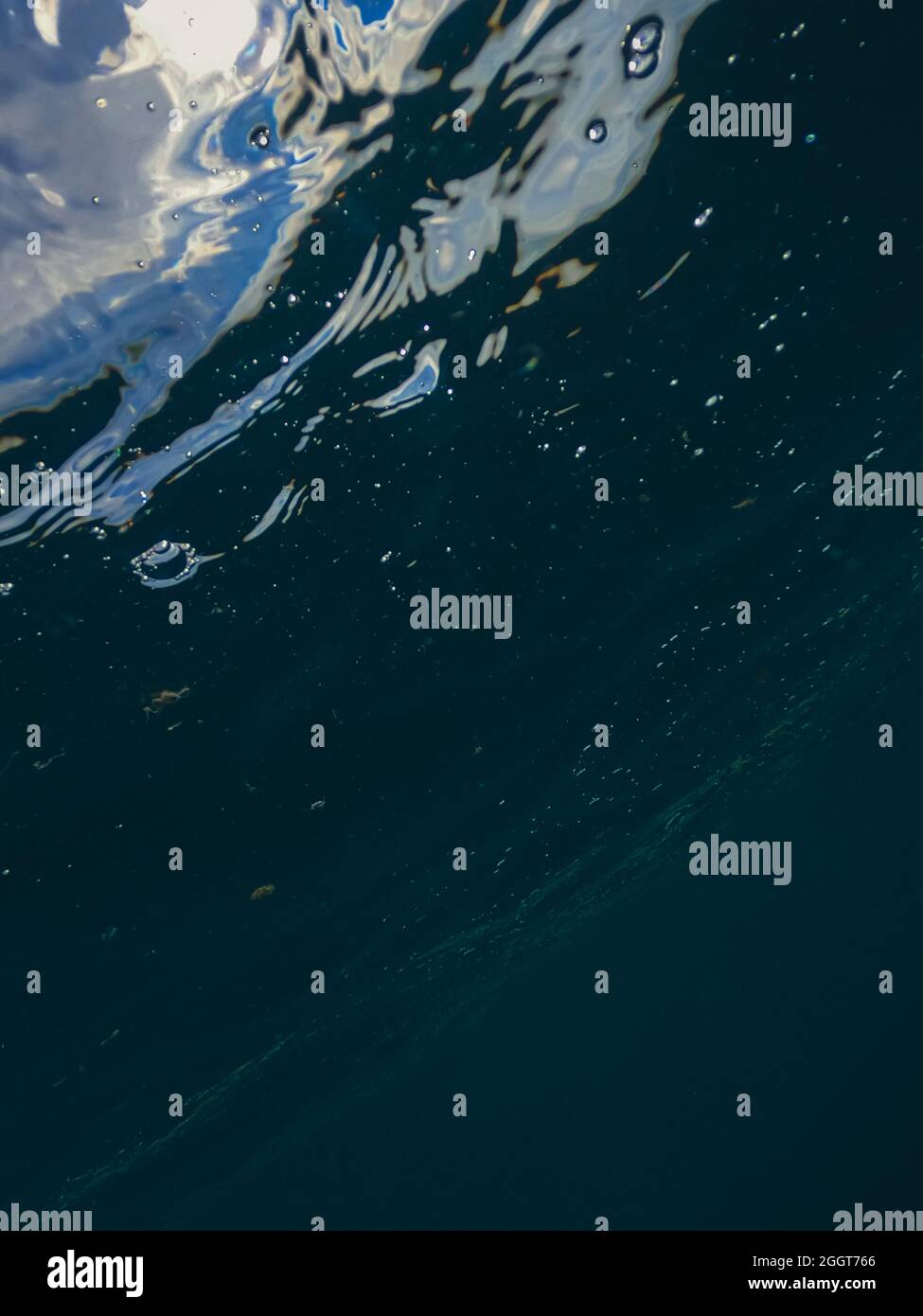 Bubbles rising to the surface in water. A rush of air bubbles surfacing in sea. Dark underwater