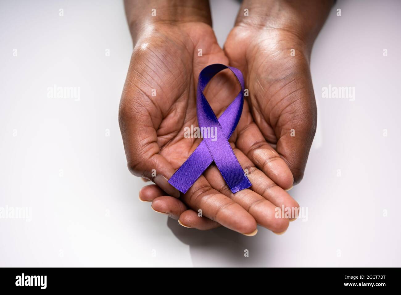 Human Hand Showing Violet Ribbon To Support Pancreatic Cancer Awareness Stock Photo