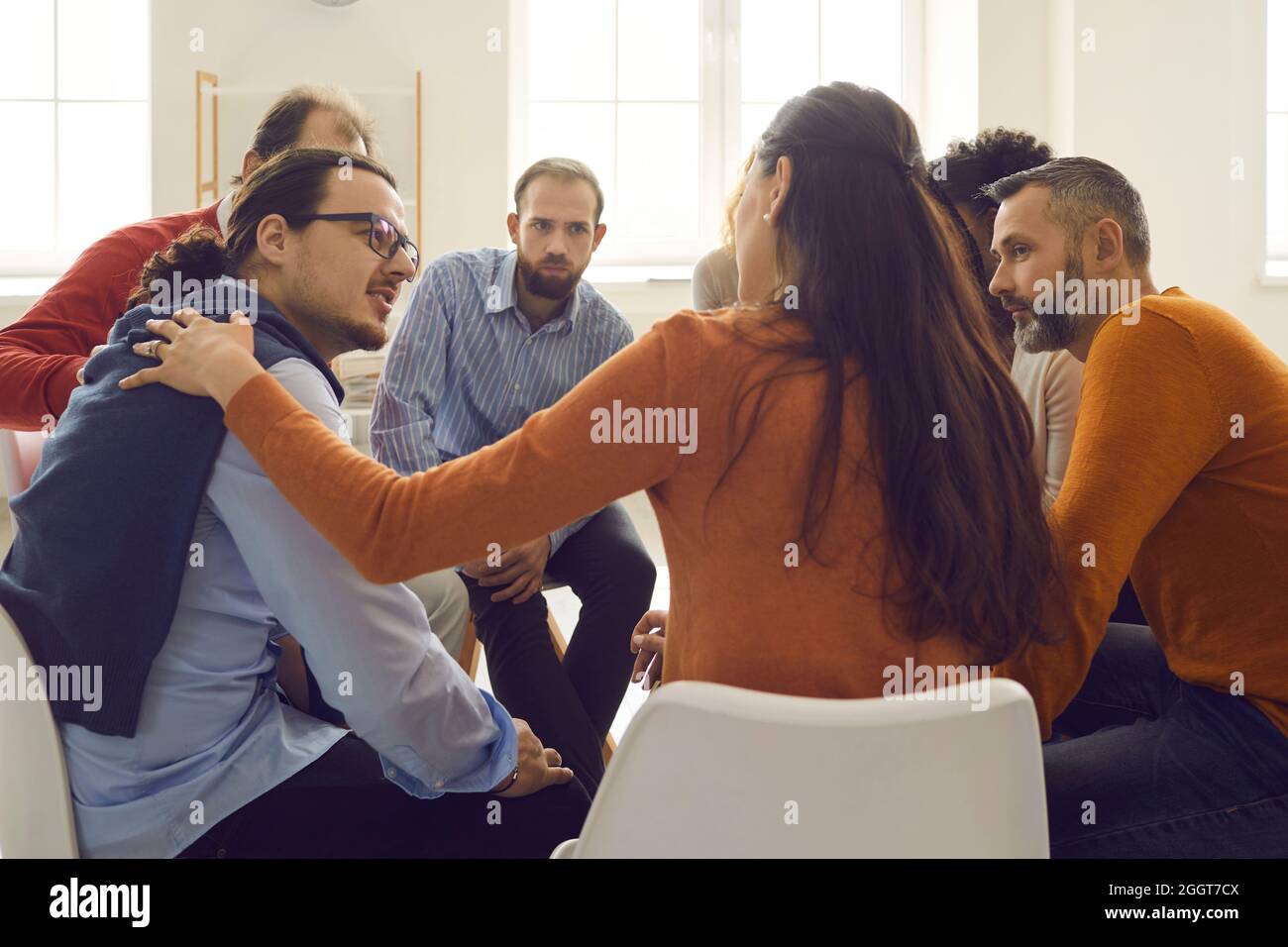Young and mature people talking and supporting each other in group therapy session Stock Photo