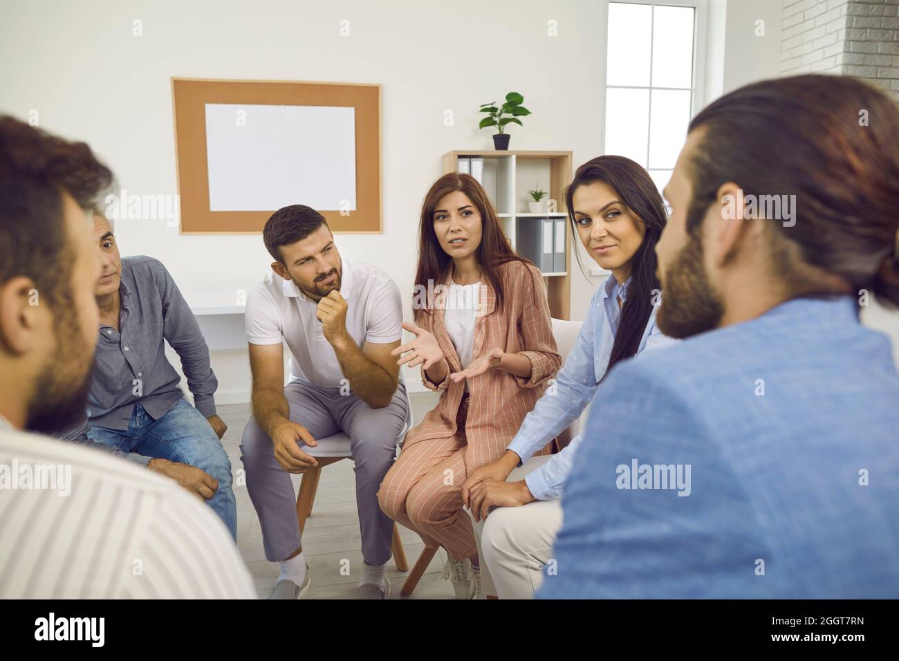 Female psychologist provides help and advice to people who came to the support group meeting. Stock Photo