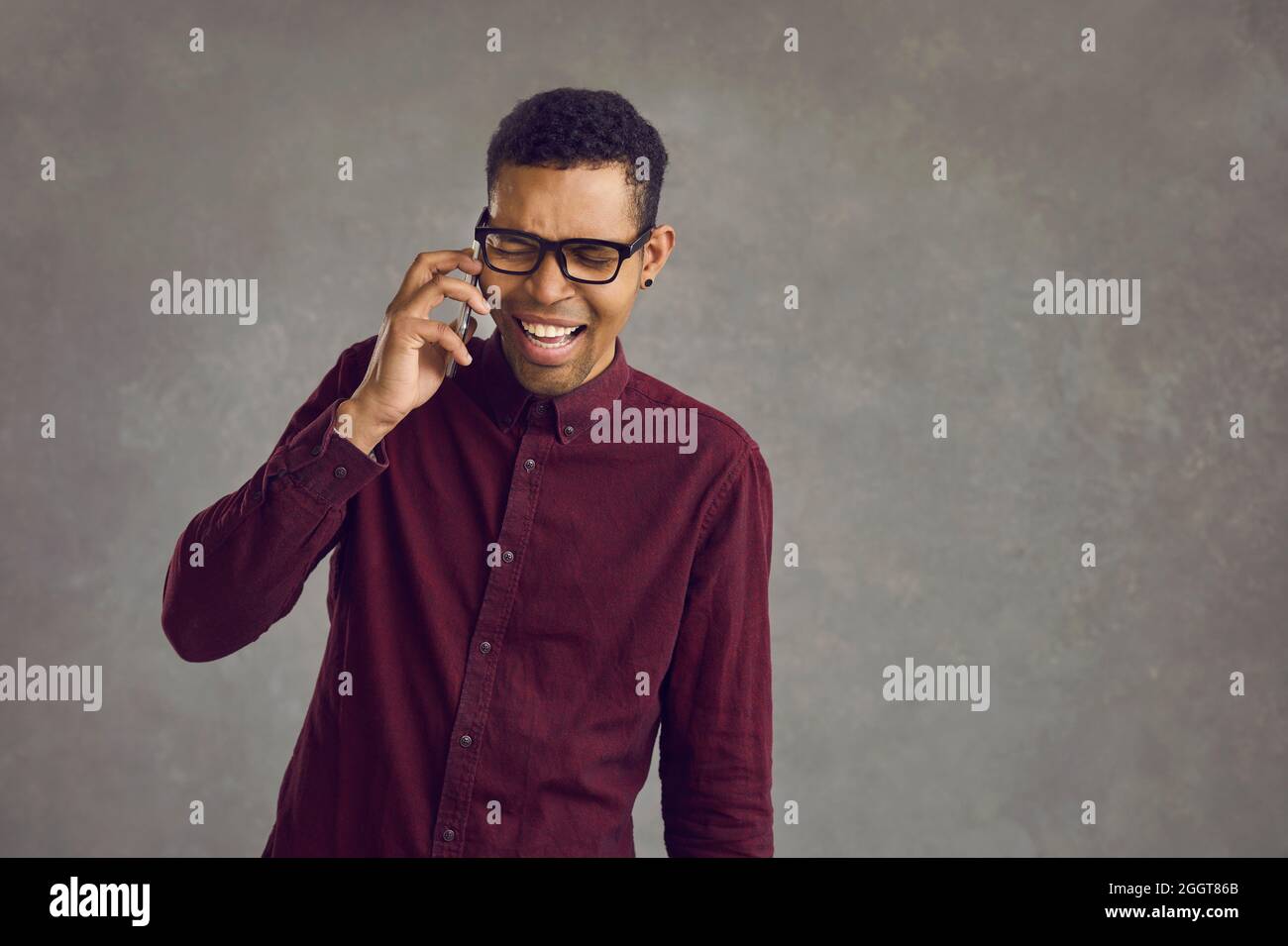 Happy young African American man feels pleasantly excited while talking on the phone. Stock Photo