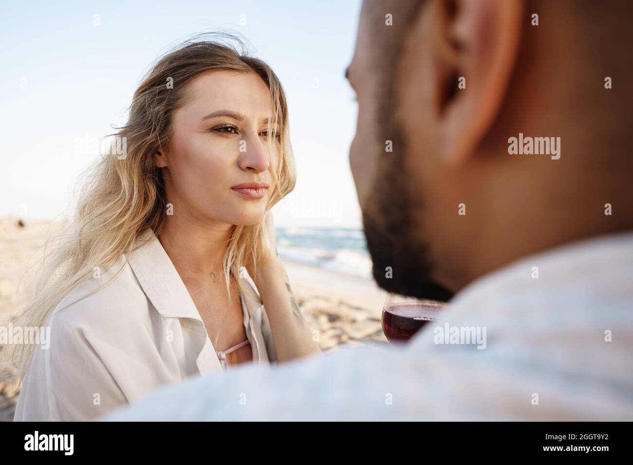 Portrait of a young couple sitting on the beach and drinking wine Stock ...
