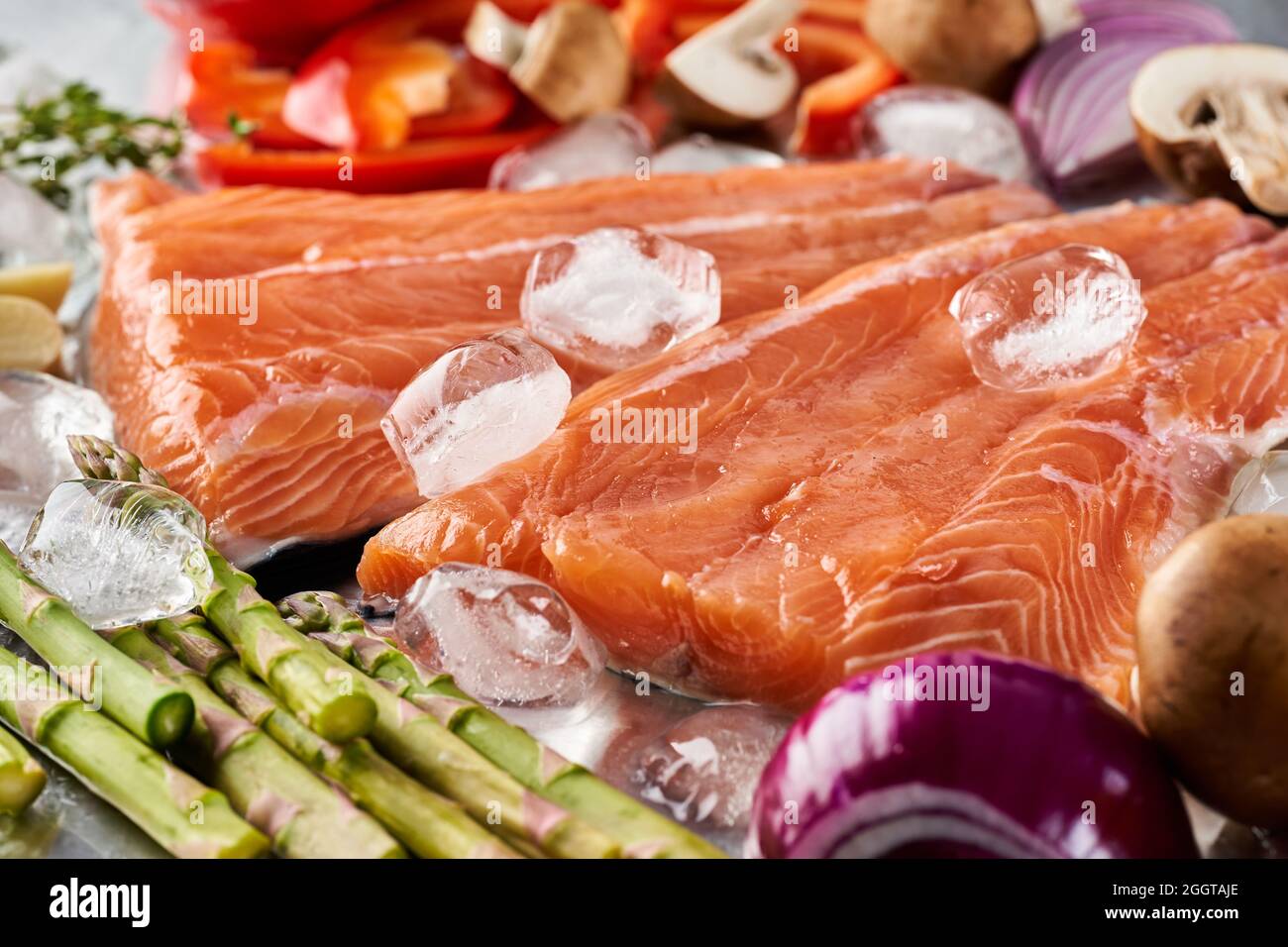 Fresh raw salmon fillets with vegetables on ice on a stainless steel ...