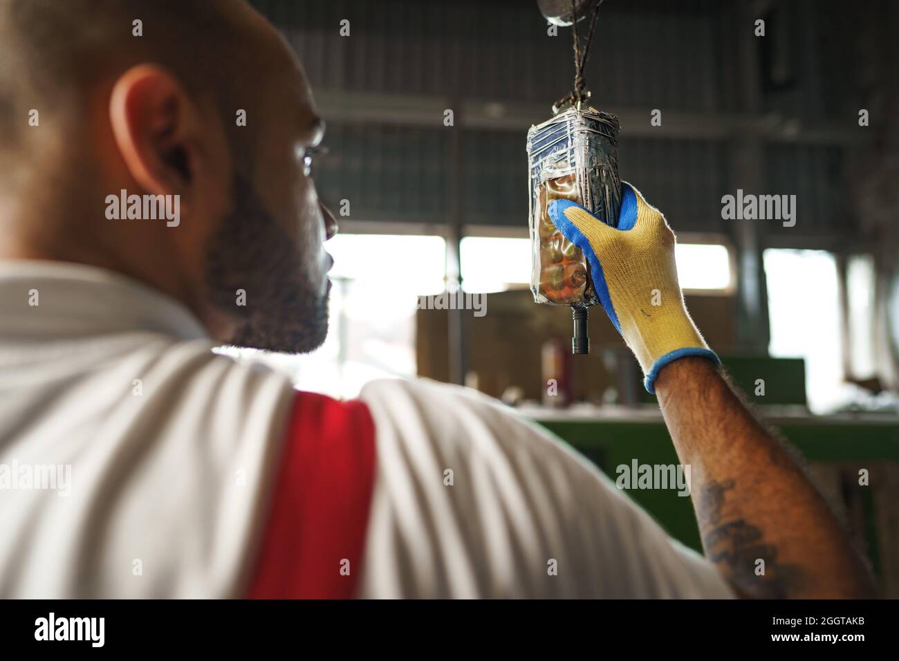 Engineer in uniform using crane controller hanging from ceiling in a factory Stock Photo
