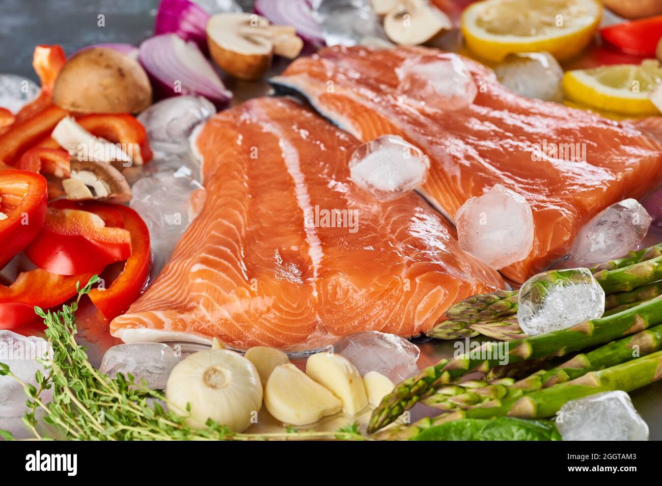 Fresh raw salmon fillets with vegetables on ice on a stainless steel ...
