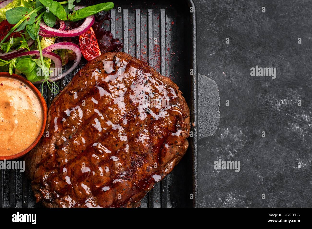 Grilled pork steak with sauce and vegetables in a skillet with place for  text Stock Photo - Alamy