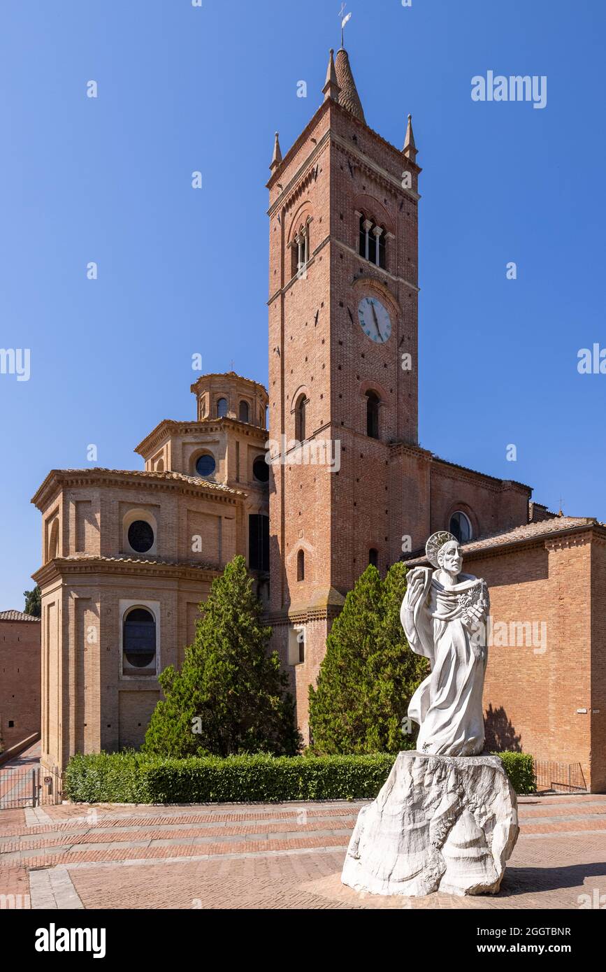 The medieval abbey of Monte Oliveto Maggiore, with the white marble statue of Saint Benedict in the foreground, and the belltower in the background Stock Photo