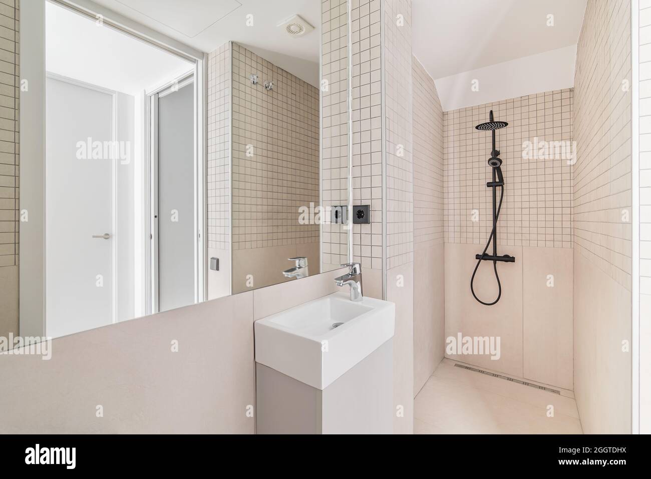 Interior of modern bathroom with beige tiles, shower and small sink ...