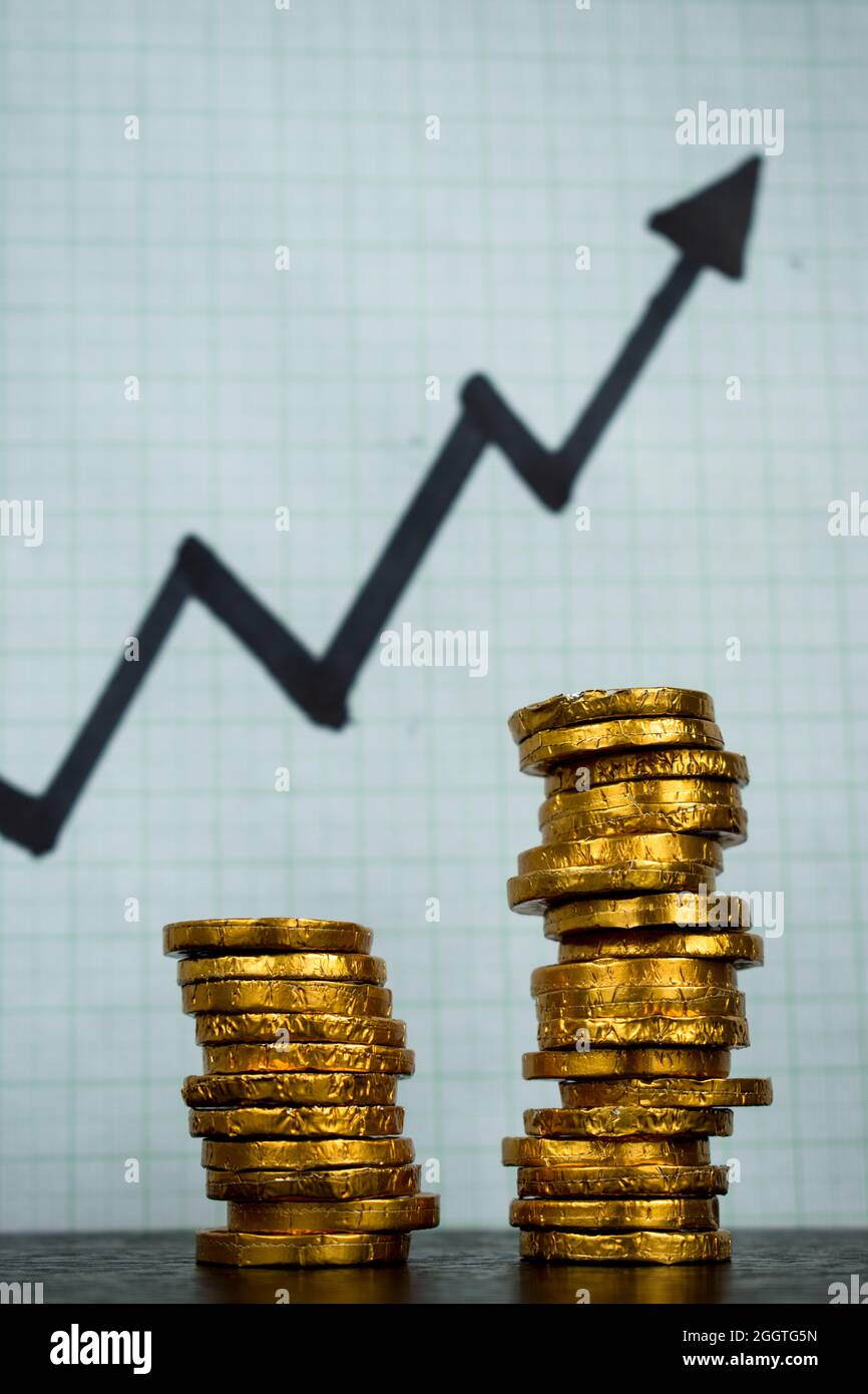Vertical closeup shot of gold coins near a rising stock arrow Stock Photo -  Alamy
