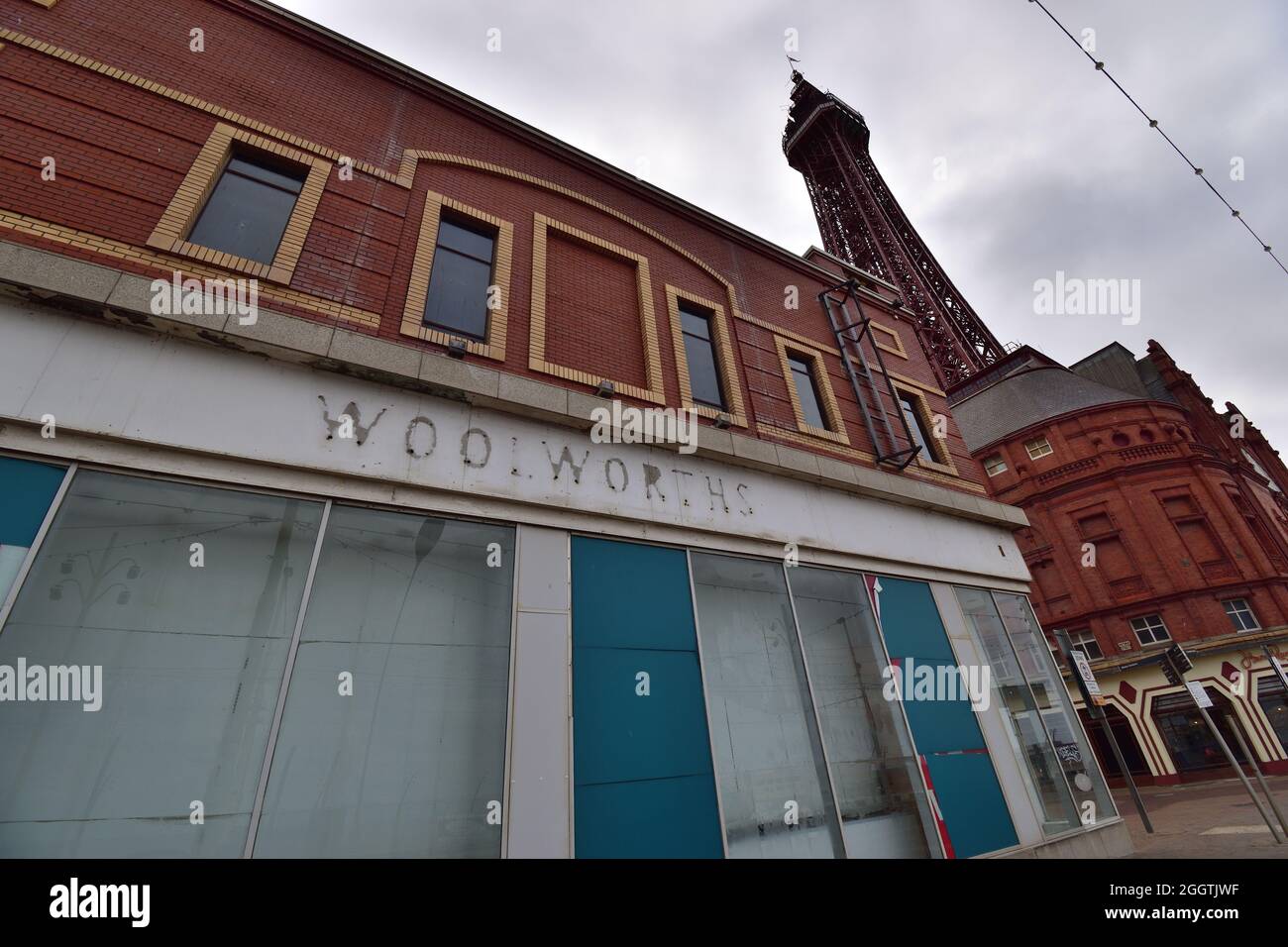 Closed down store on Blackpool Promenade with Blackpool Tower in background, old Woolworths signage outline visable Stock Photo