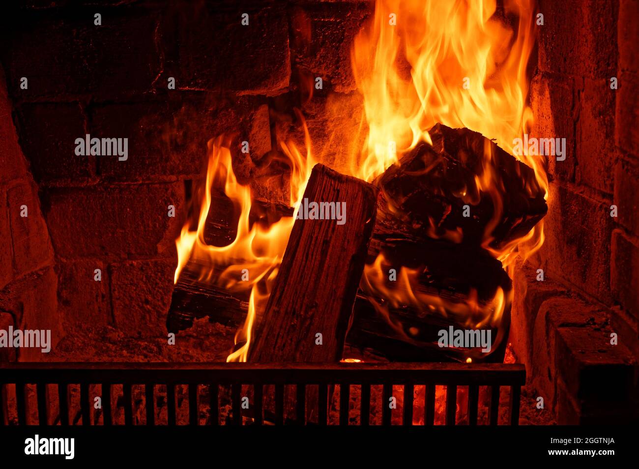 An open fire with a fire grate in front is burning well Stock Photo