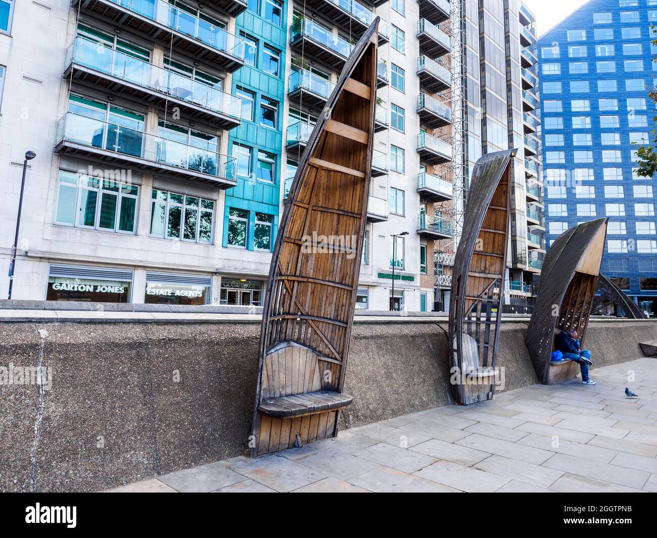 Sidewalk benches made out of wood and shaped like the front of a boat near Lambeth bridge - London, England Stock Photo